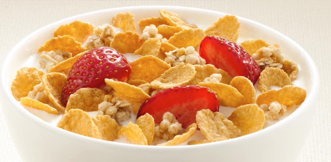A bowl of Fibre 1 Cereal, Honey Clusters flavour, with milk and sliced strawberries.